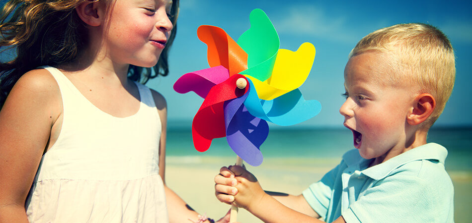 children holding rainbow spinning wheel on beach